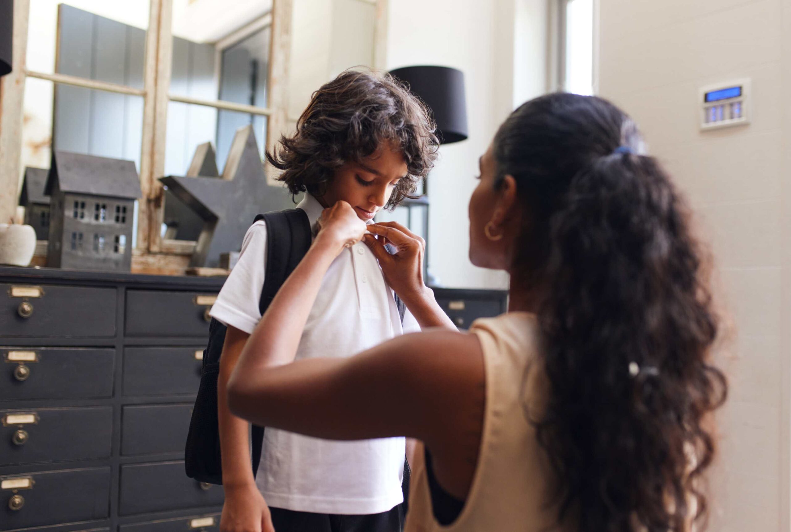 Mom buttoning her son's shirt.