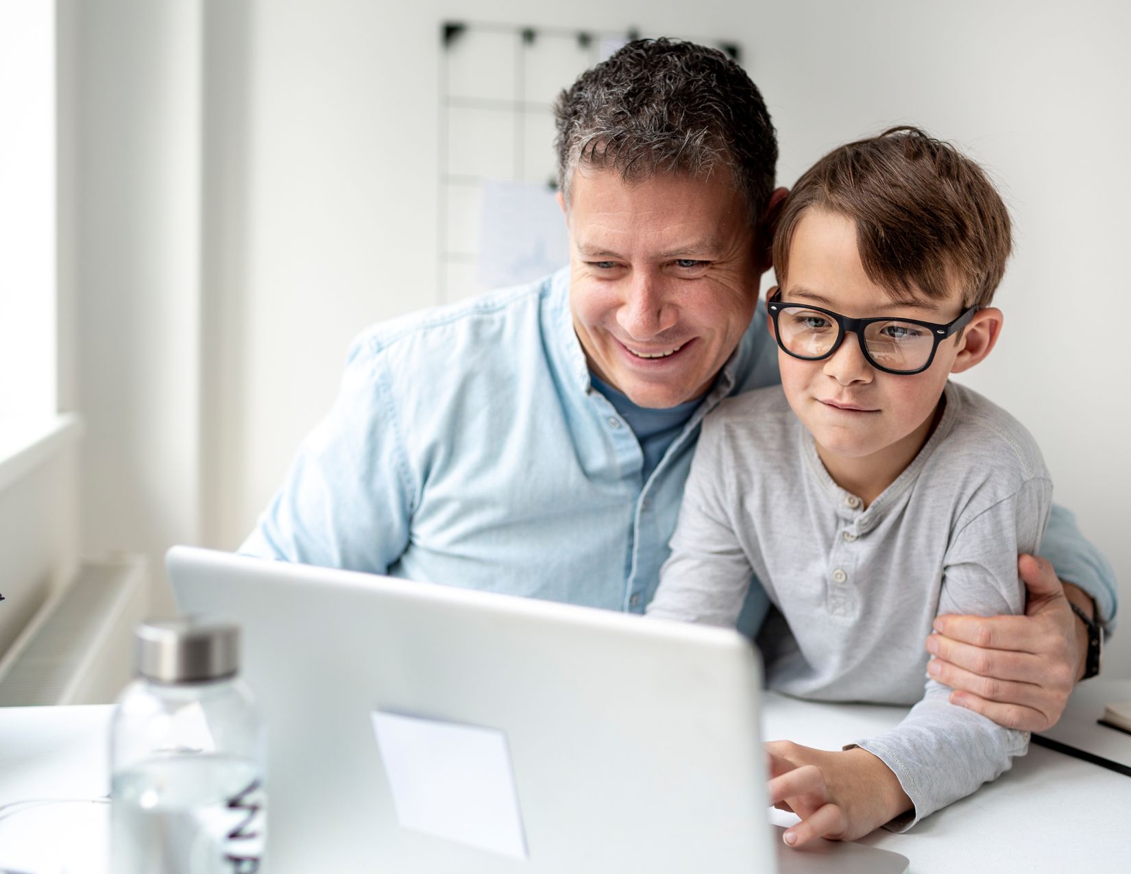 Dad helping son do work on a laptop