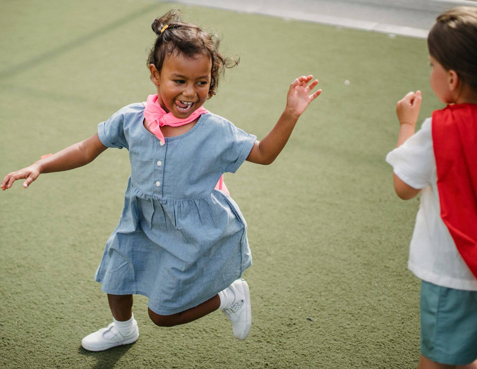 Two excited young girls running in a playground.
